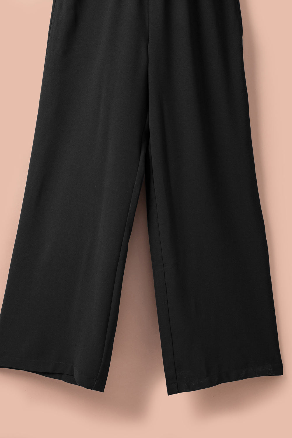 A stylish black jumpsuit featuring flutter sleeves, a smocked bodice, and wide leg bottoms, perfect for any occasion.