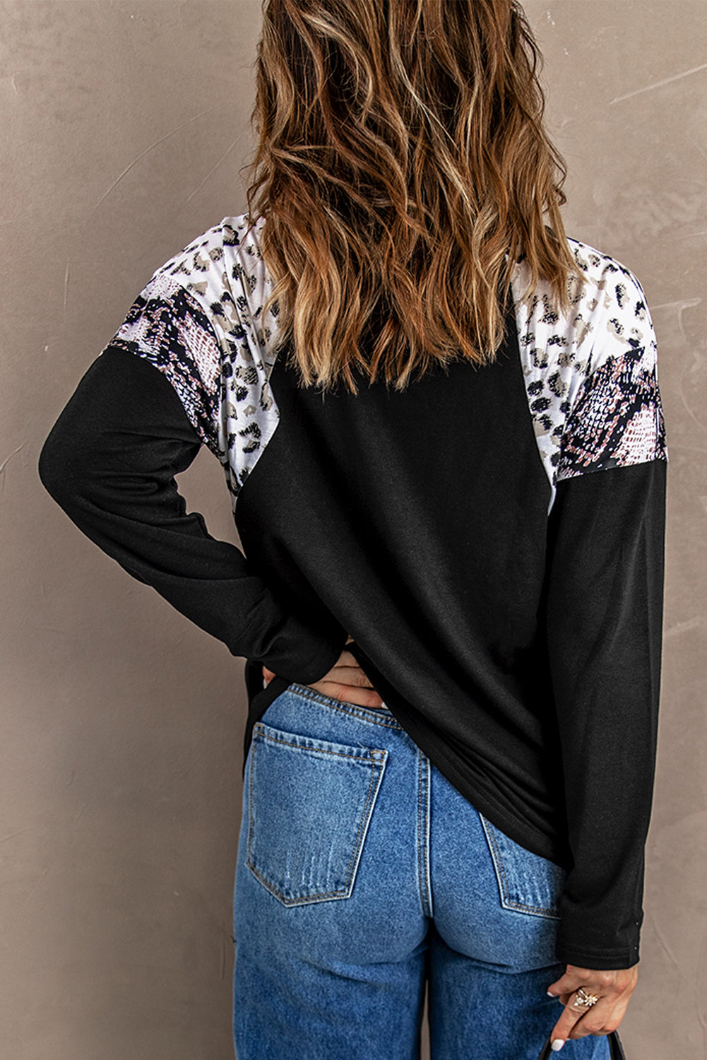 Black long sleeve top featuring a leopard snakeskin print, showcasing its stylish design and comfortable fabric.