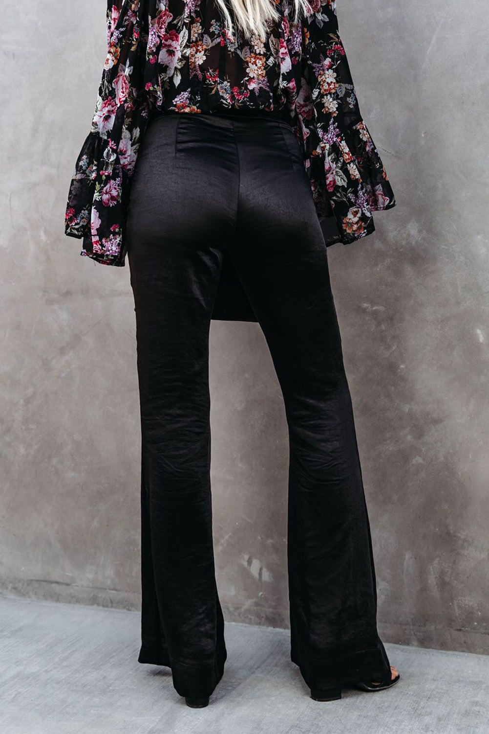 A pair of elegant black satin flare tailored pants with a high waist and pleated details, showcasing a luxurious fabric and stylish silhouette.