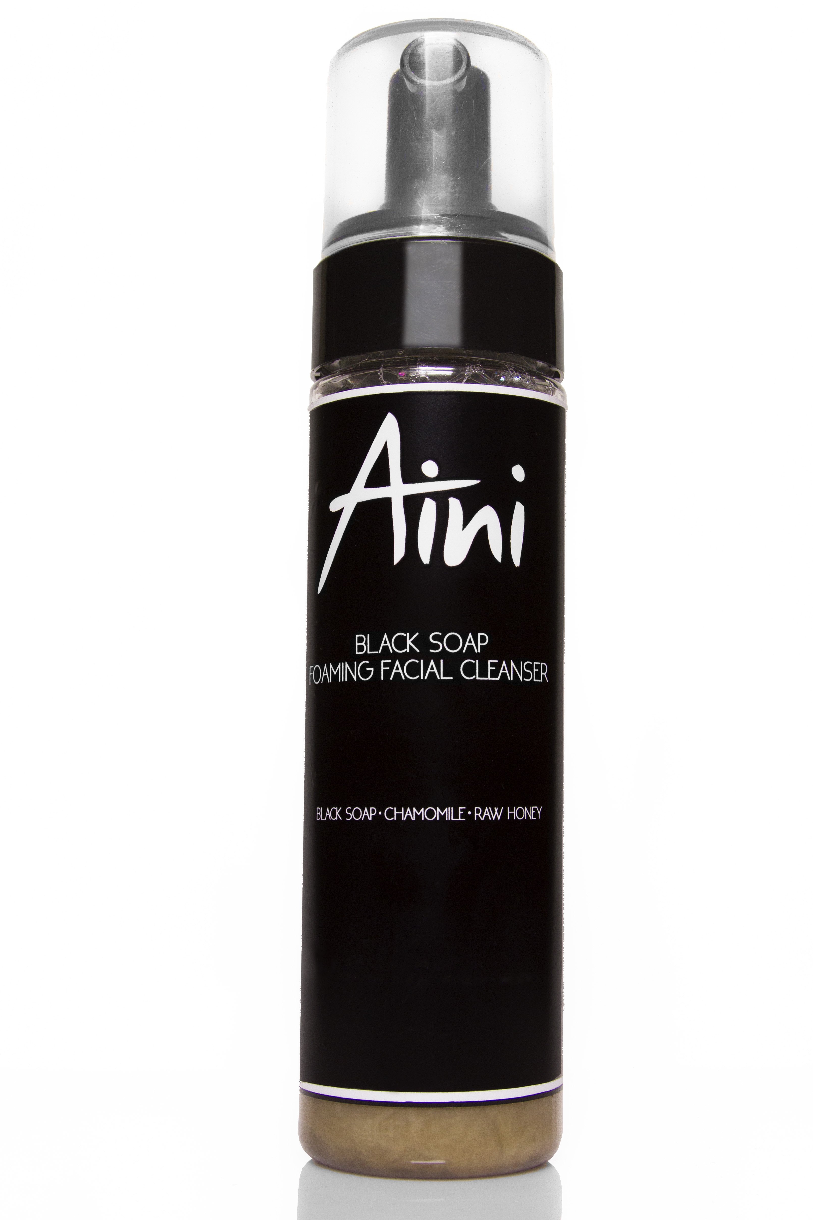 A bottle of Black Soap Foaming Facial Cleanser with a rich lather, showcasing its natural ingredients like chamomile and honey.