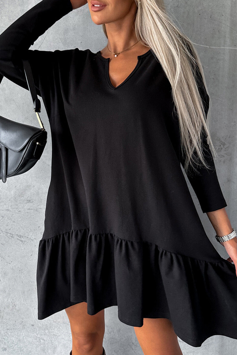 A stylish black dress featuring a split neck, long sleeves, and a ruffled hem, perfect for various occasions.