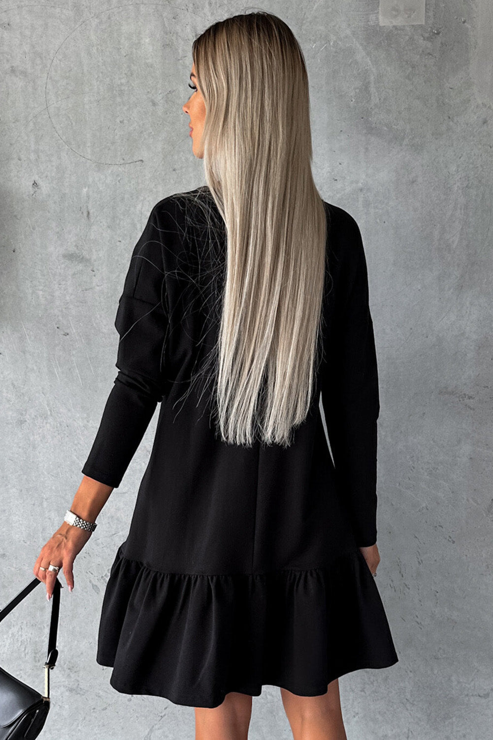 A stylish black dress featuring a split neck, long sleeves, and a ruffled hem, perfect for various occasions.