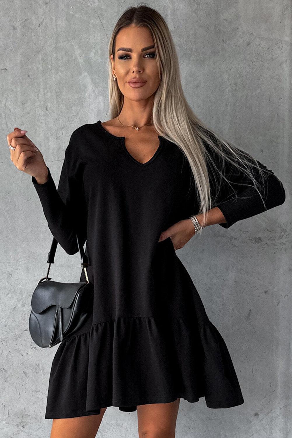 A stylish black dress featuring a split neck, long sleeves, and a ruffled hem, perfect for various occasions.