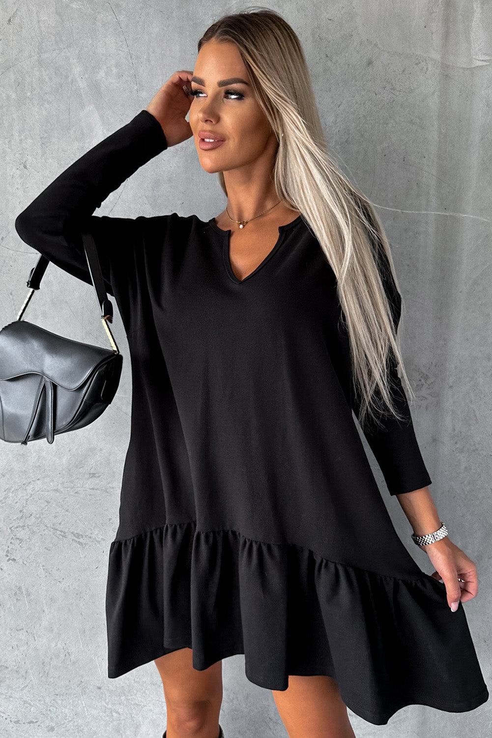 A stylish black dress featuring a split neck, long sleeves, and a ruffled hem, perfect for various occasions.