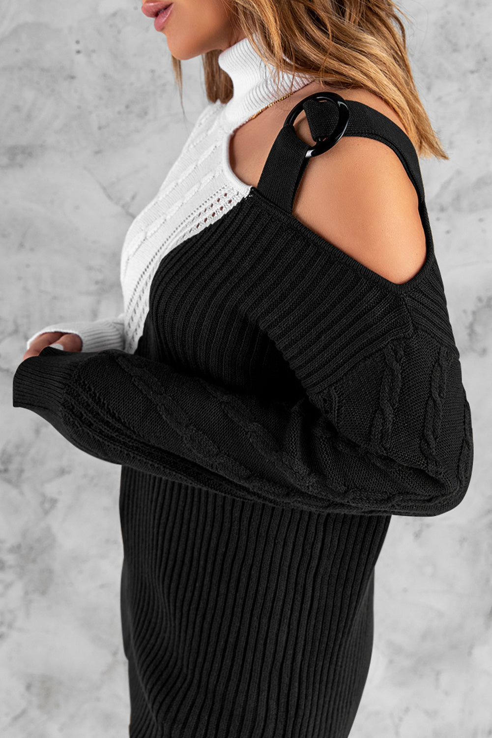 A stylish black turtleneck sweater featuring cold shoulder design and buckled decor, perfect for chic winter outfits.