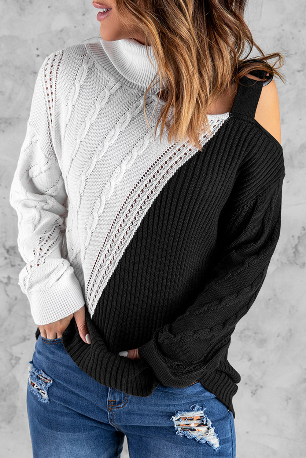 A stylish black turtleneck sweater featuring cold shoulder design and buckled decor, perfect for chic winter outfits.