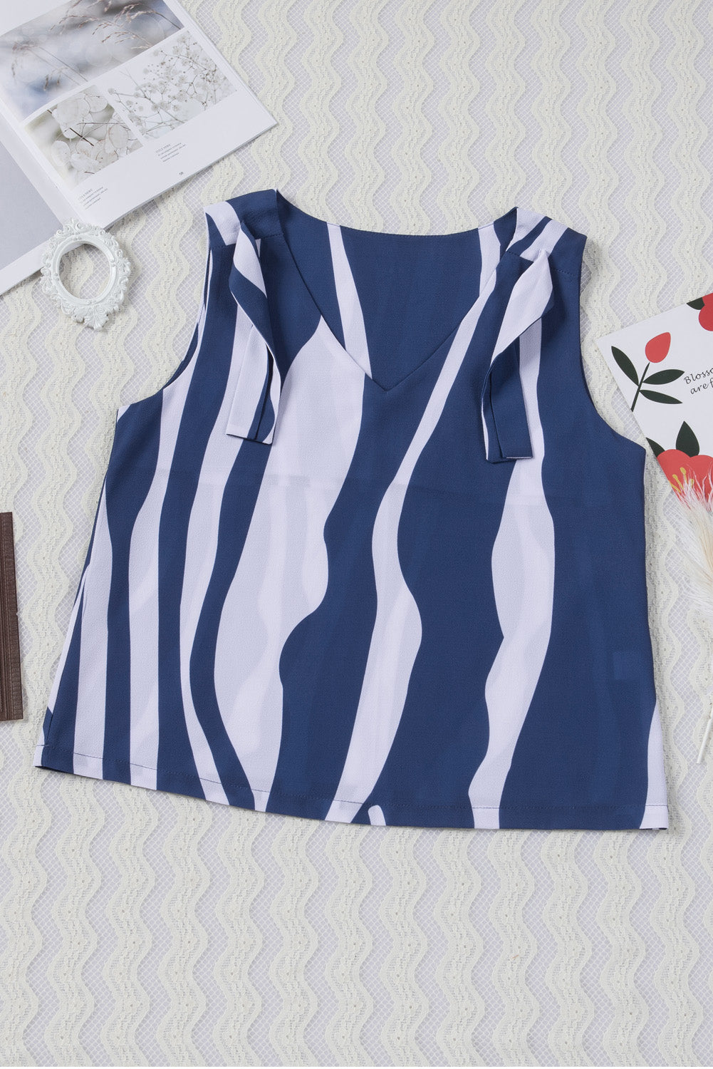 A stylish blue tank top featuring an abstract striped pattern and knotted straps, perfect for casual and formal occasions.