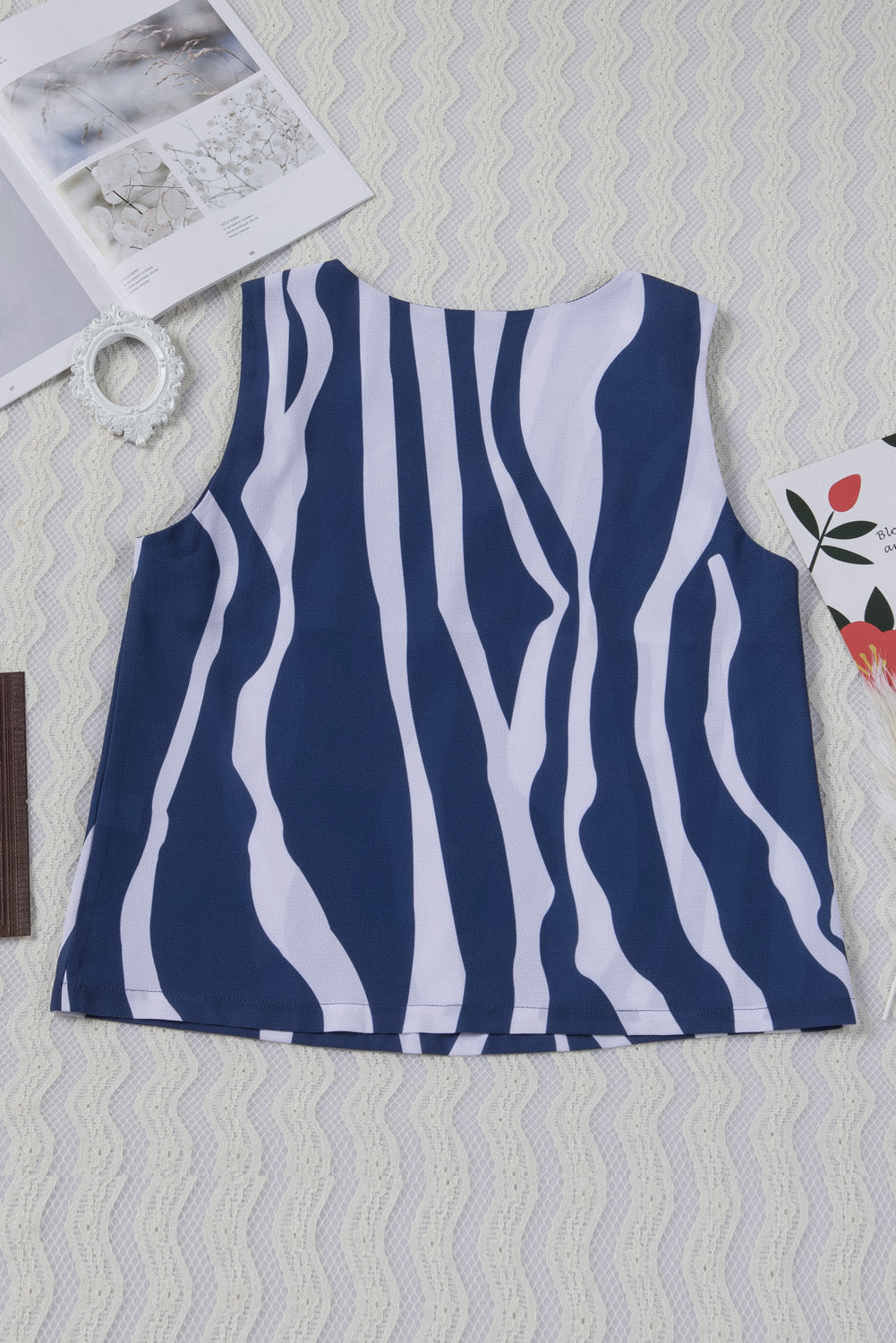 A stylish blue tank top featuring an abstract striped pattern and knotted straps, perfect for casual and formal occasions.