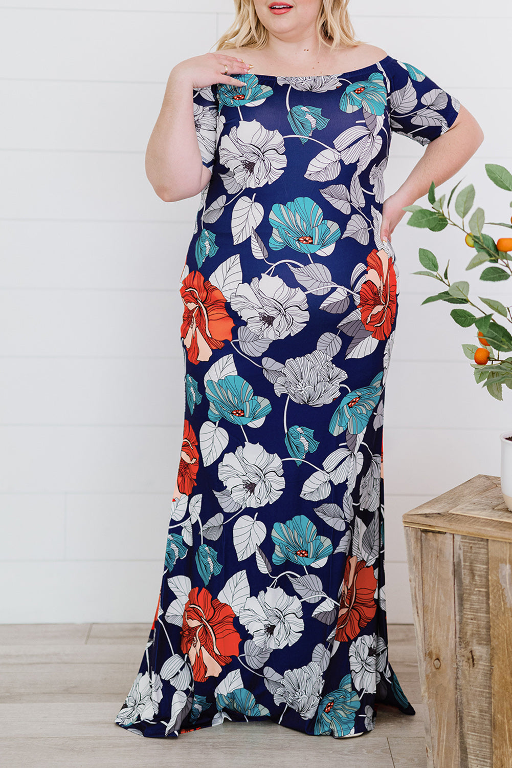 A beautiful plus size maxi dress featuring a blue green floral print and an off-the-shoulder design, perfect for elegant occasions.