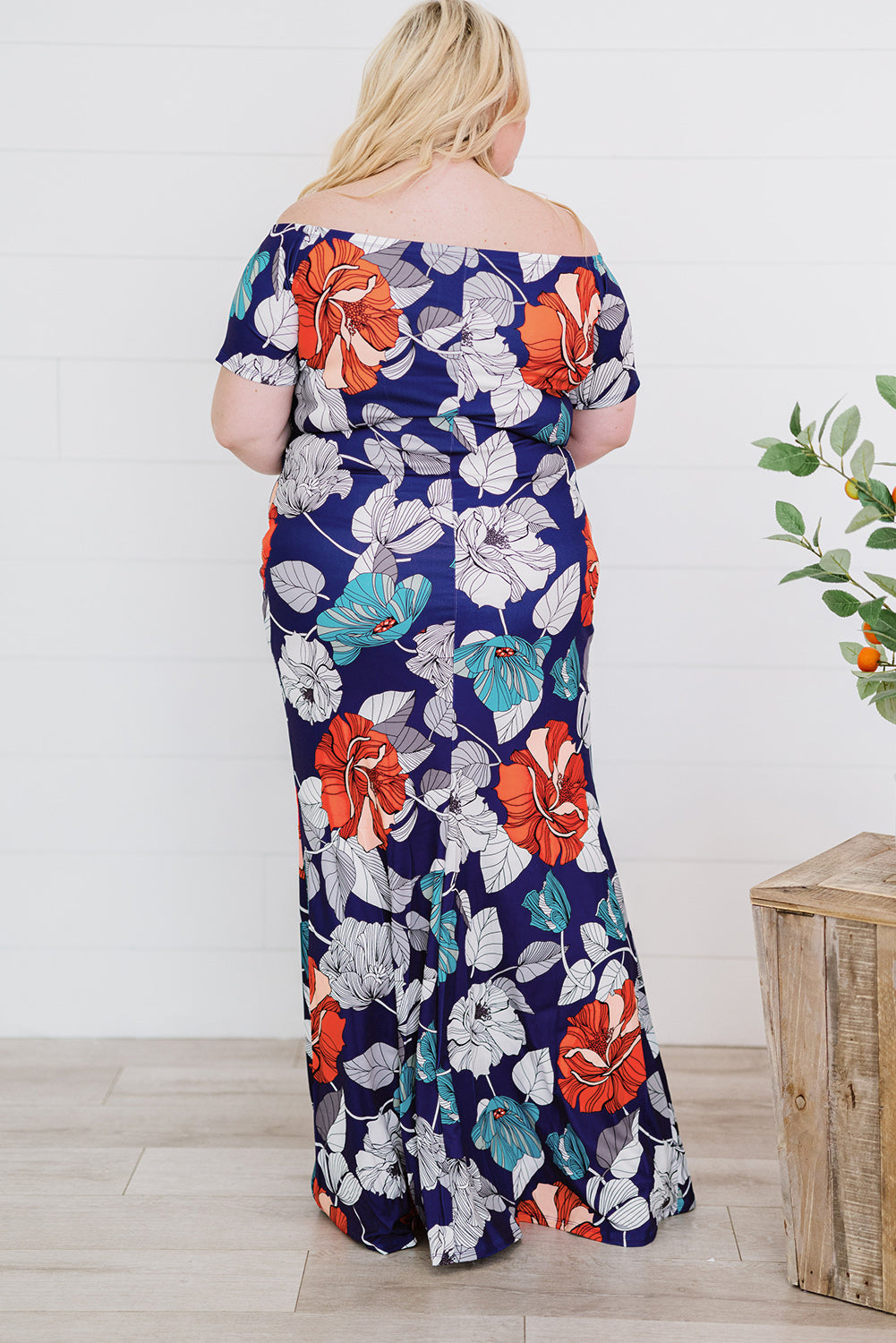 A beautiful plus size maxi dress featuring a blue green floral print and an off-the-shoulder design, perfect for elegant occasions.