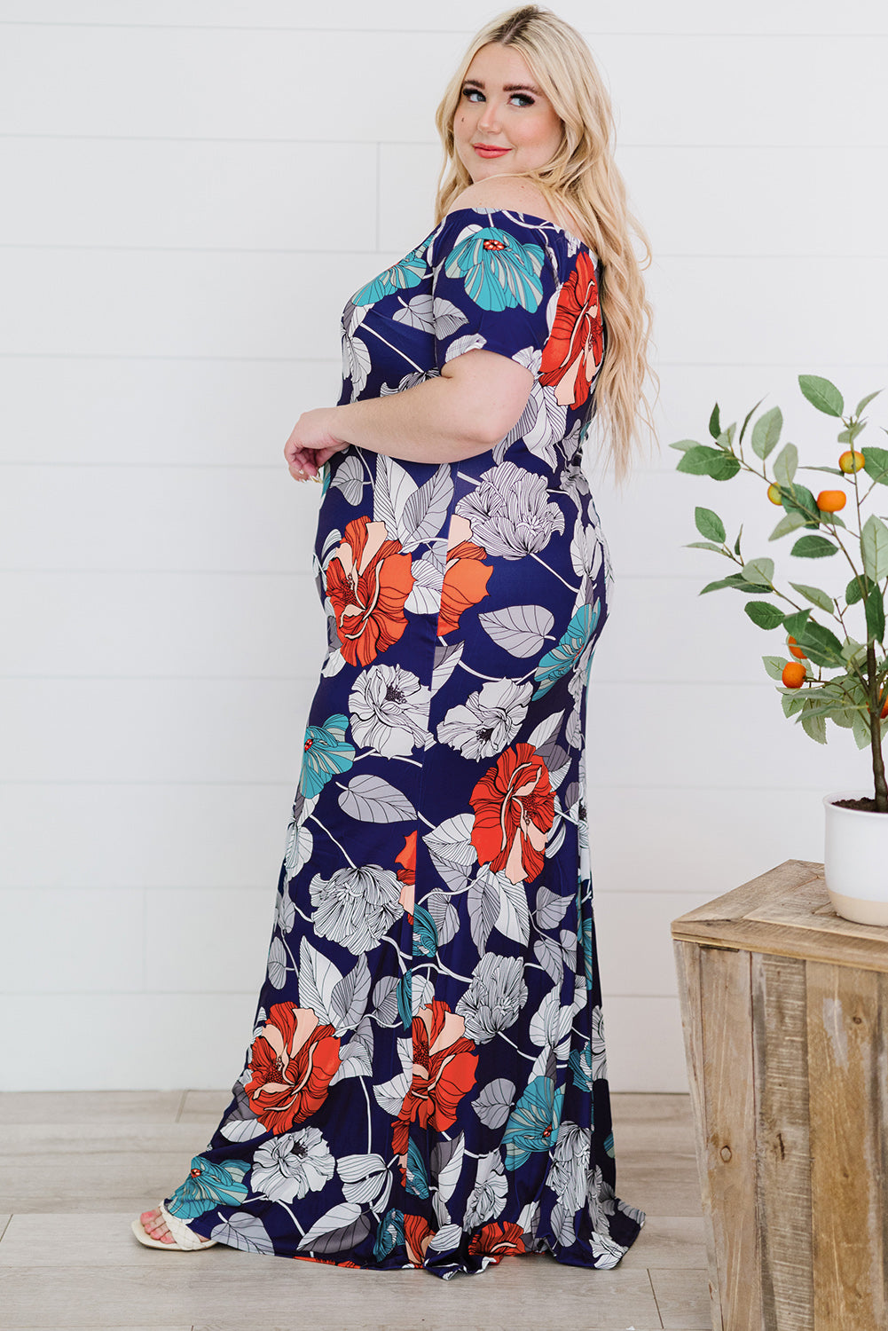 A beautiful plus size maxi dress featuring a blue green floral print and an off-the-shoulder design, perfect for elegant occasions.