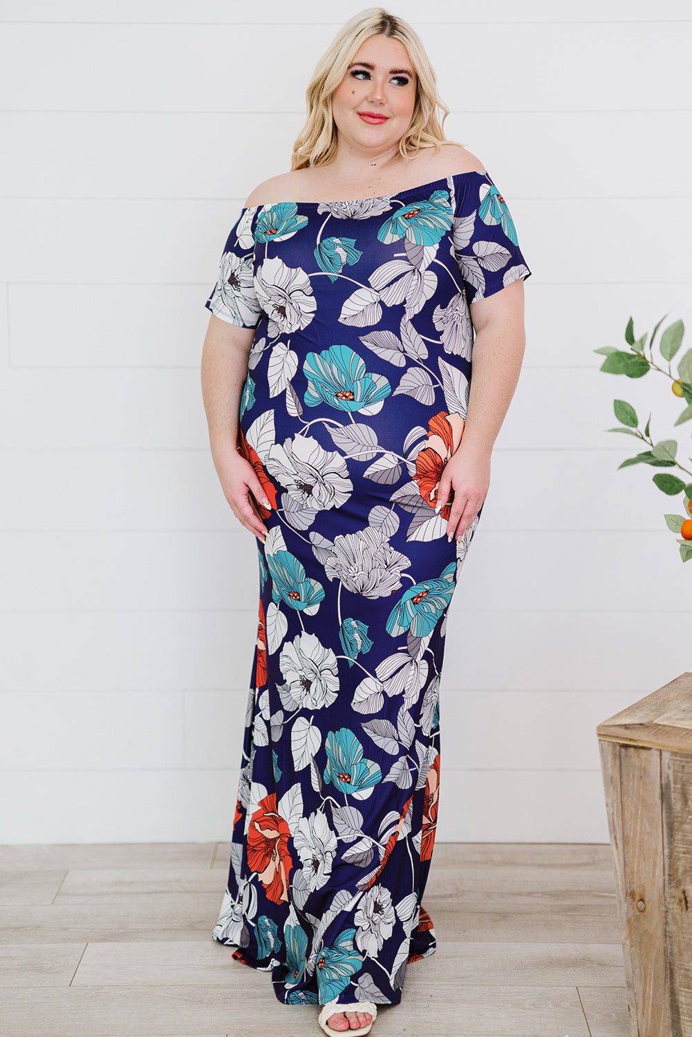 A beautiful plus size maxi dress featuring a blue green floral print and an off-the-shoulder design, perfect for elegant occasions.