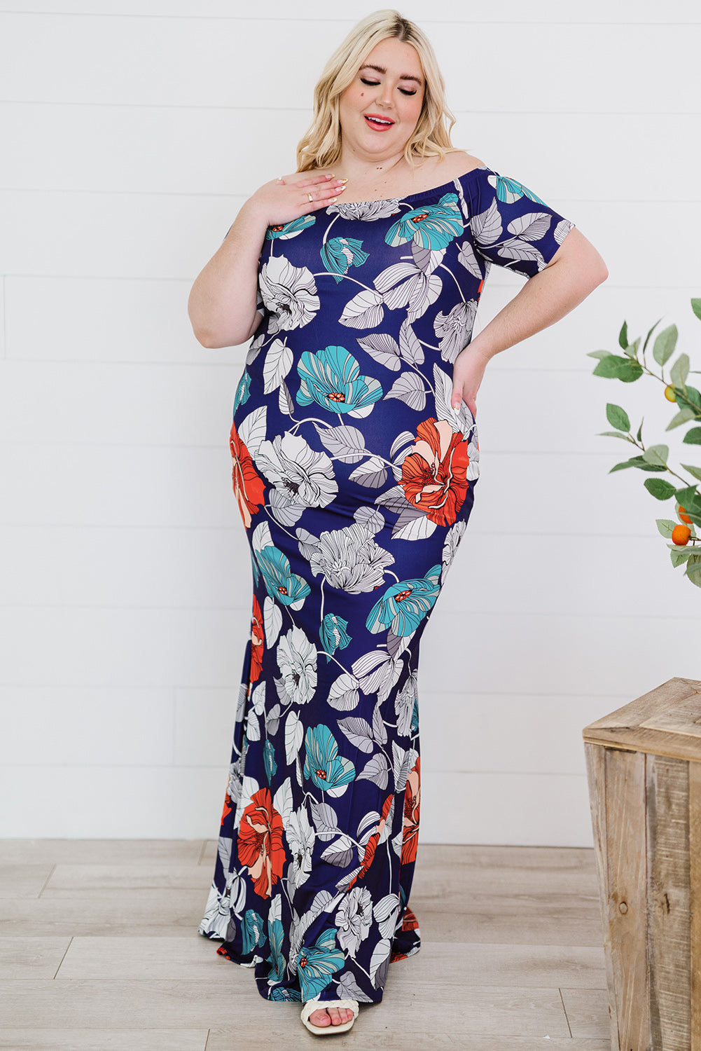 A beautiful plus size maxi dress featuring a blue green floral print and an off-the-shoulder design, perfect for elegant occasions.