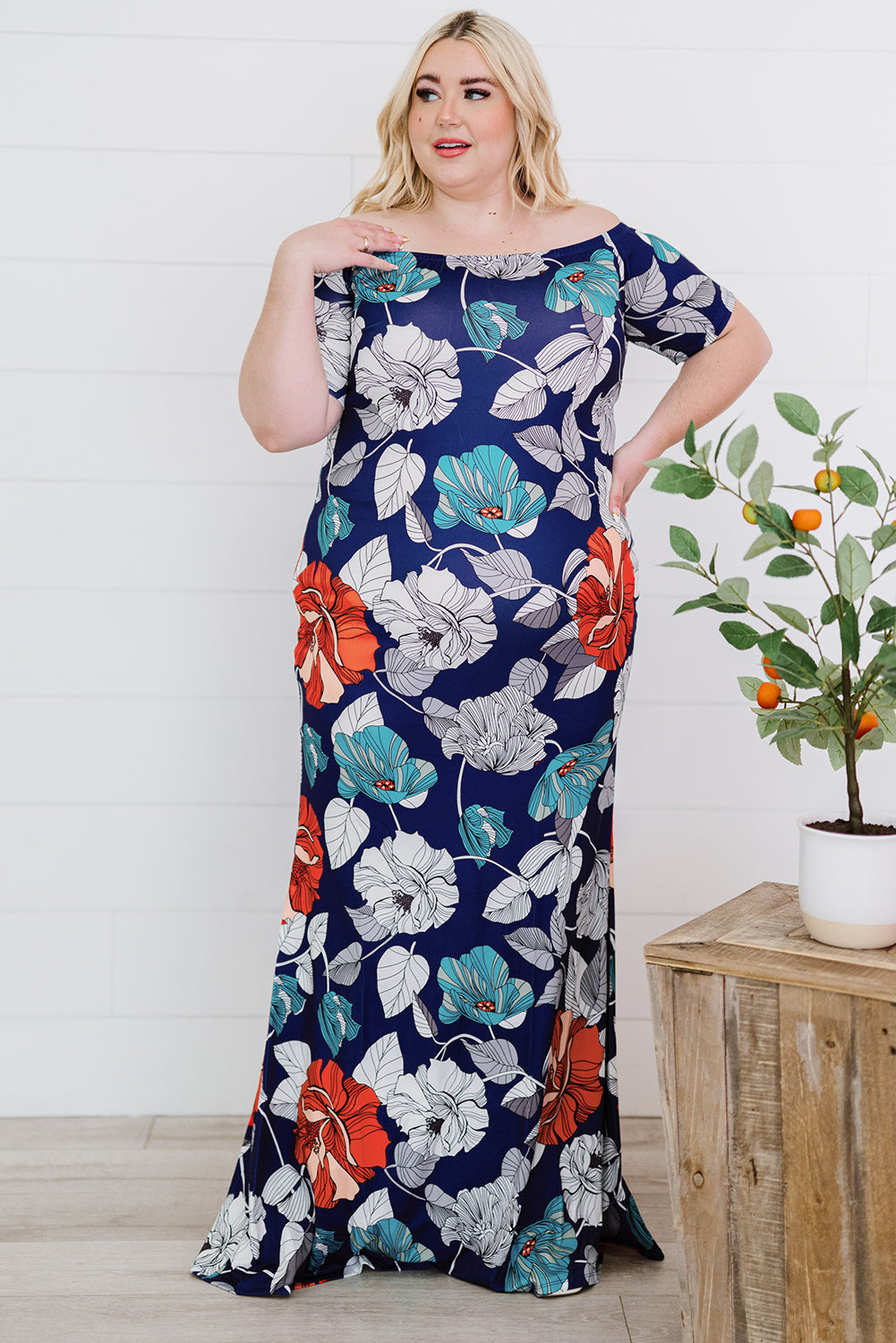 A beautiful plus size maxi dress featuring a blue green floral print and an off-the-shoulder design, perfect for elegant occasions.