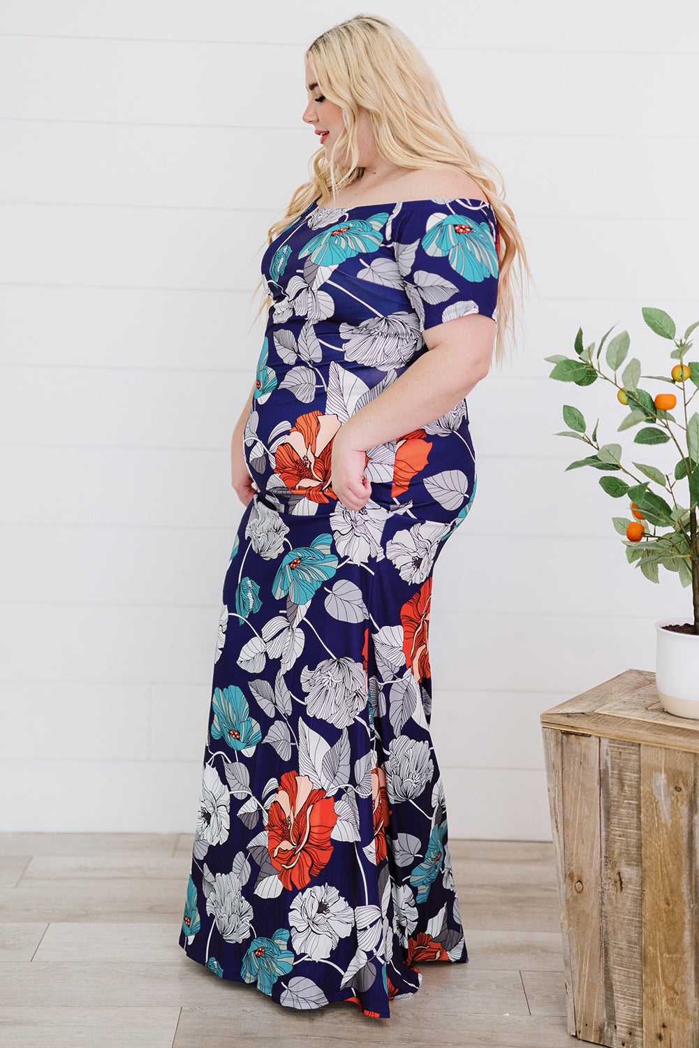 A beautiful plus size maxi dress featuring a blue green floral print and an off-the-shoulder design, perfect for elegant occasions.