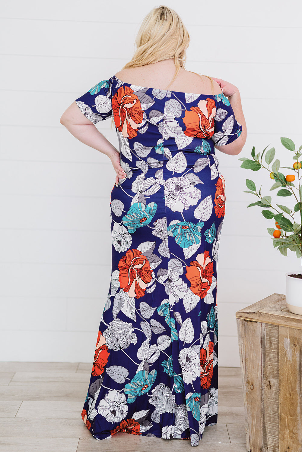 A beautiful plus size maxi dress featuring a blue green floral print and an off-the-shoulder design, perfect for elegant occasions.