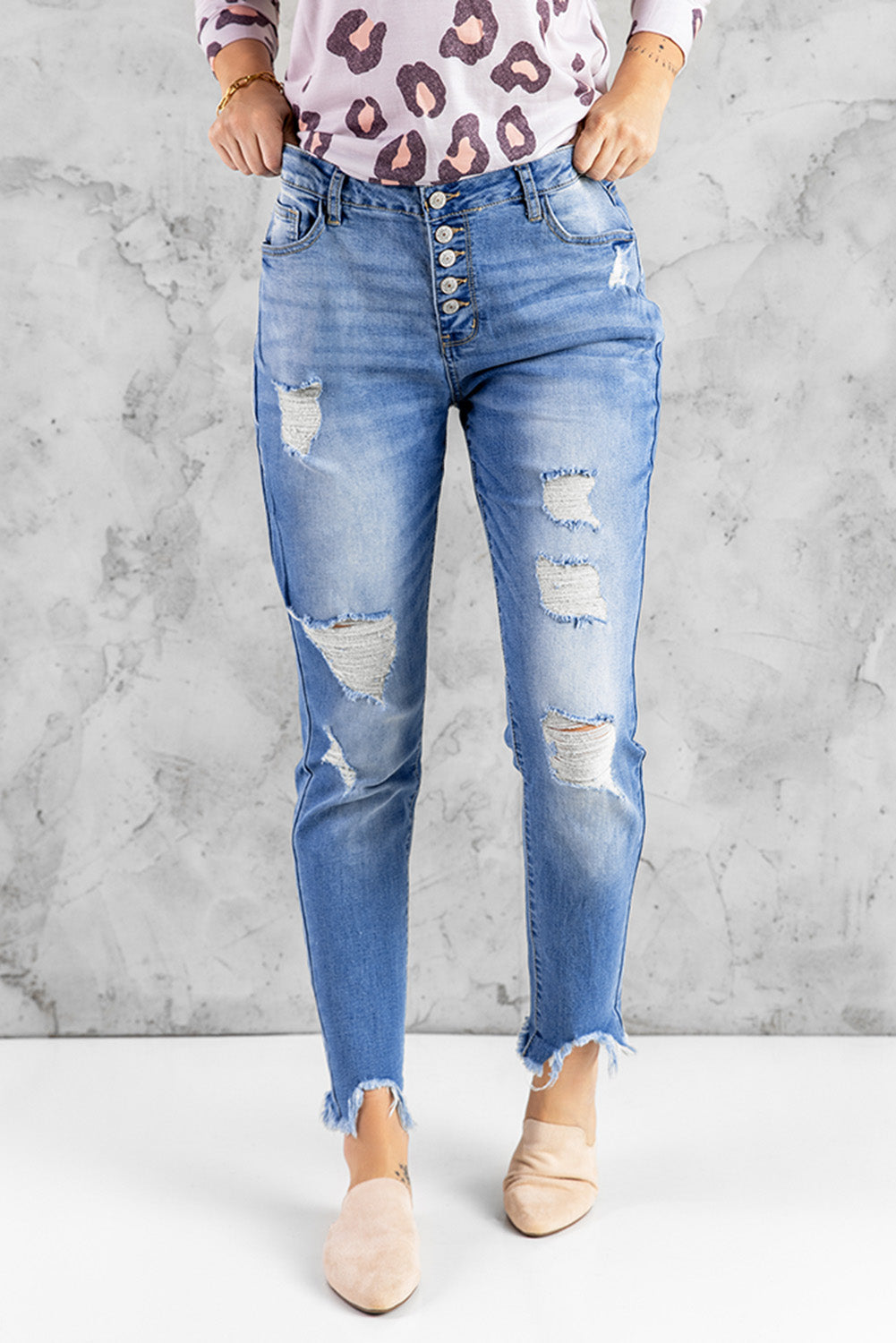 Blue high rise skinny jeans with button front and frayed ankle hem, showcasing a medium wash and distressed details.