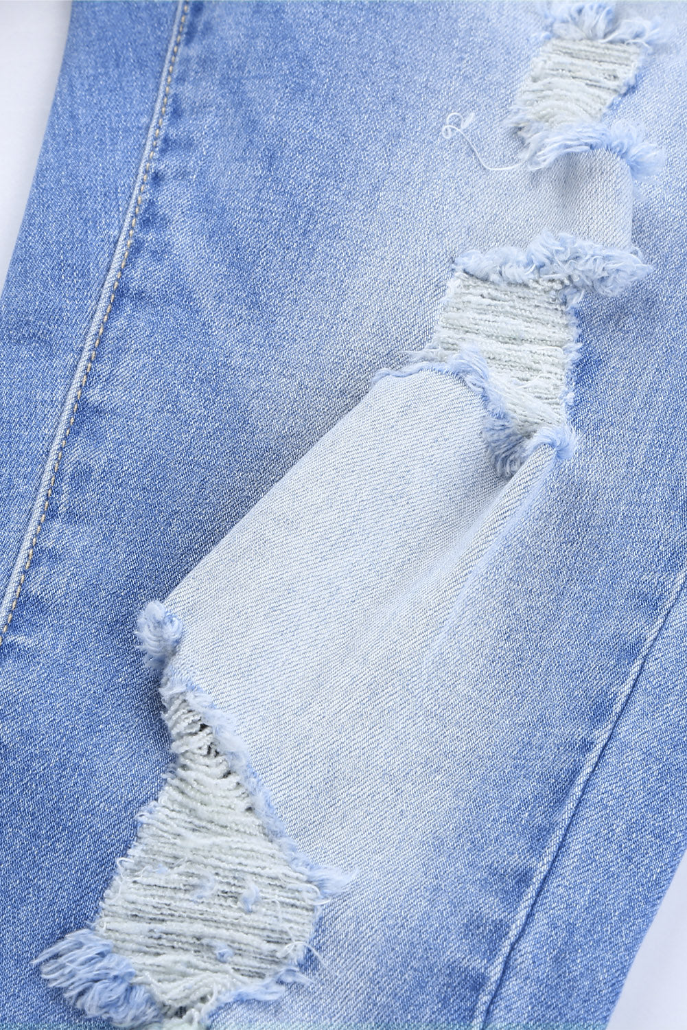 Blue high rise skinny jeans with button front and frayed ankle hem, showcasing a medium wash and distressed details.