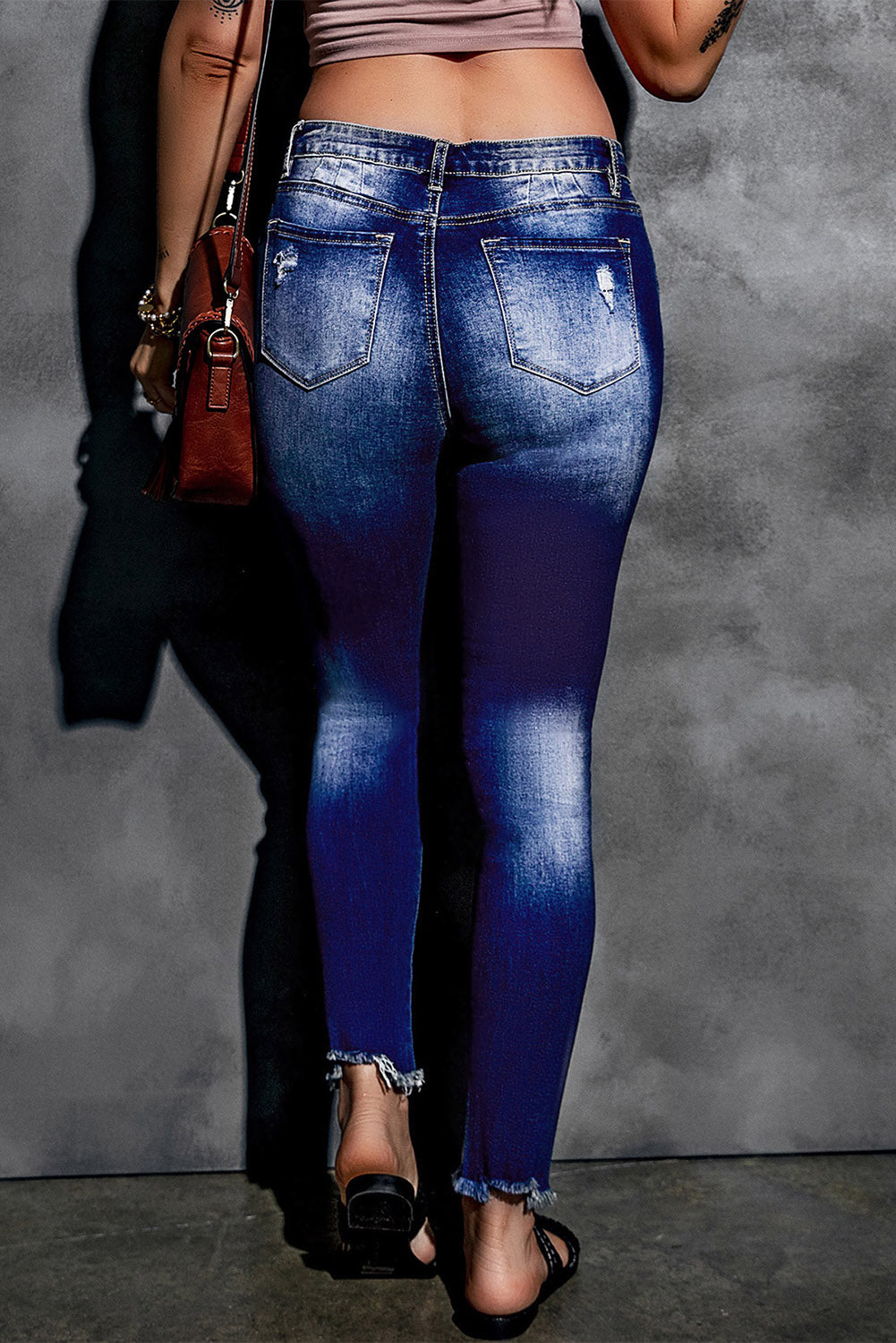 Blue high rise skinny jeans with button front and frayed ankle hem, showcasing a medium wash and distressed details.