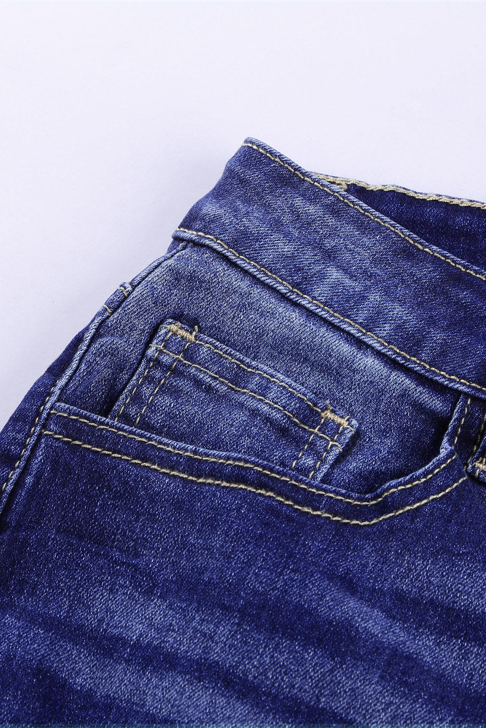 Blue high rise skinny jeans with button front and frayed ankle hem, showcasing a medium wash and distressed details.