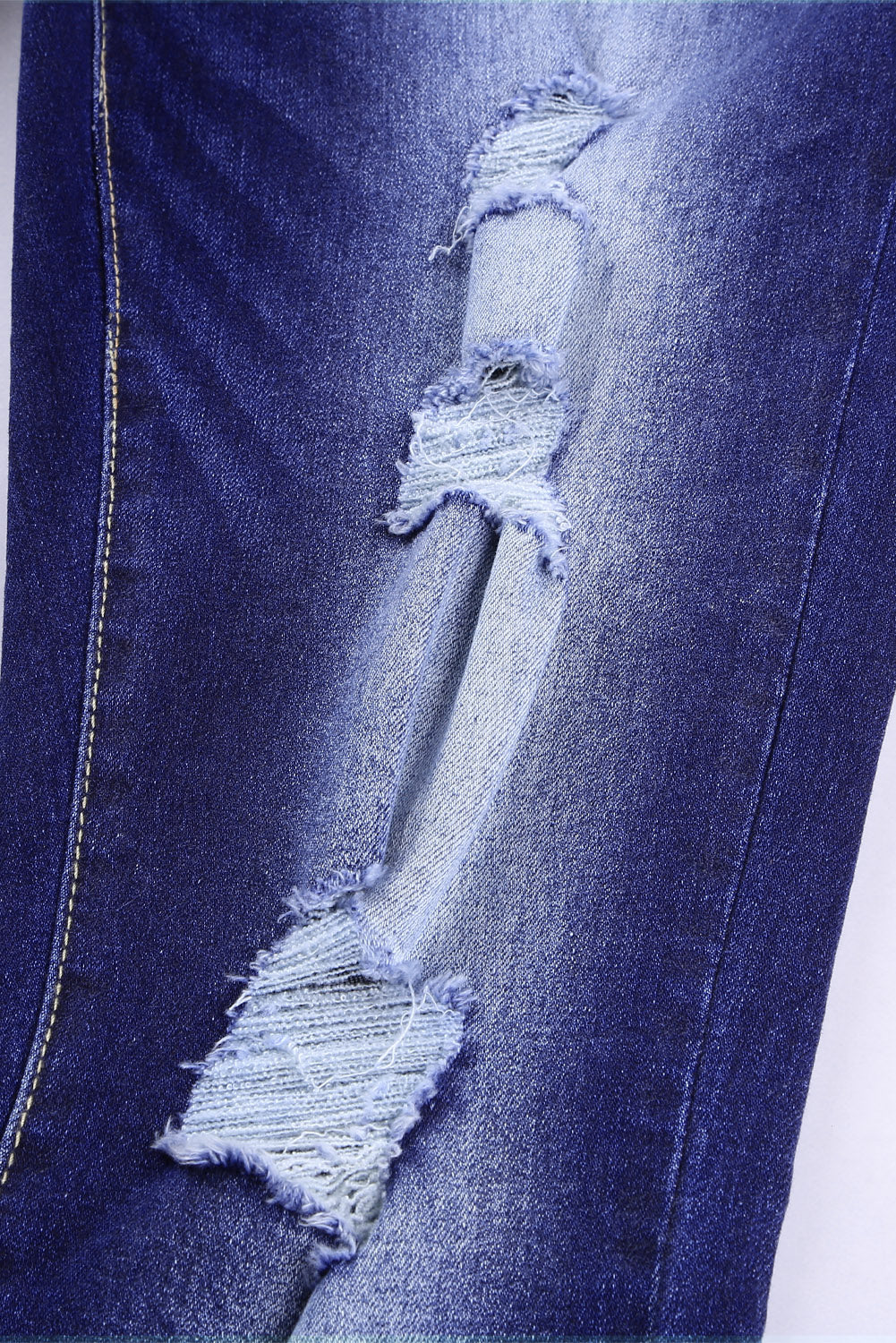 Blue high rise skinny jeans with button front and frayed ankle hem, showcasing a medium wash and distressed details.