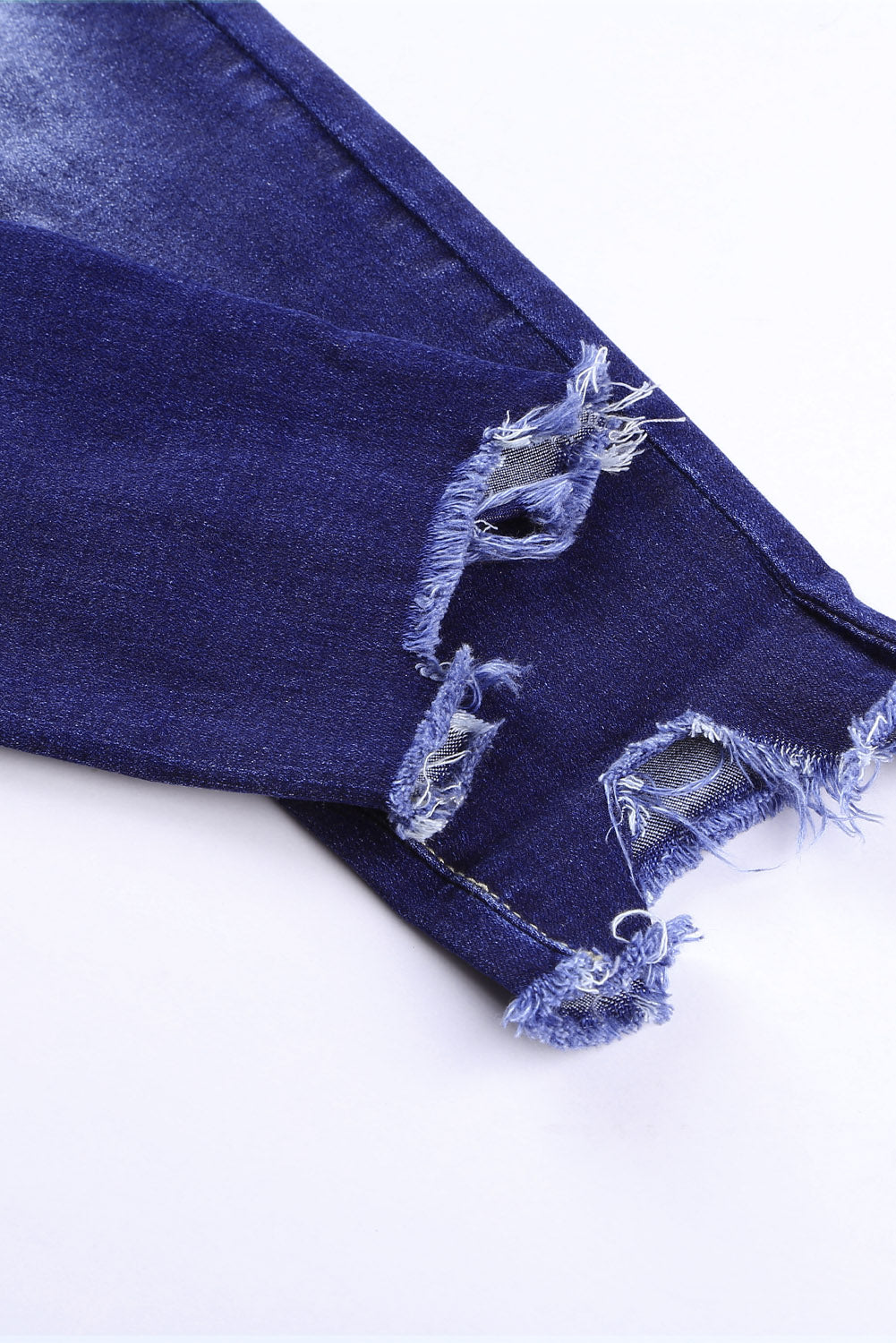 Blue high rise skinny jeans with button front and frayed ankle hem, showcasing a medium wash and distressed details.