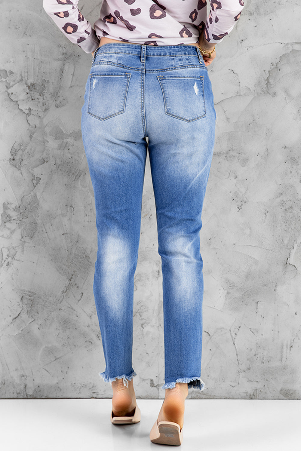 Blue high rise skinny jeans with button front and frayed ankle hem, showcasing a medium wash and distressed details.