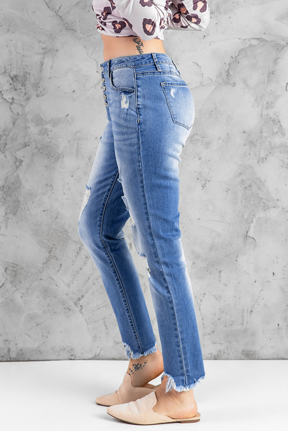 Blue high rise skinny jeans with button front and frayed ankle hem, showcasing a medium wash and distressed details.