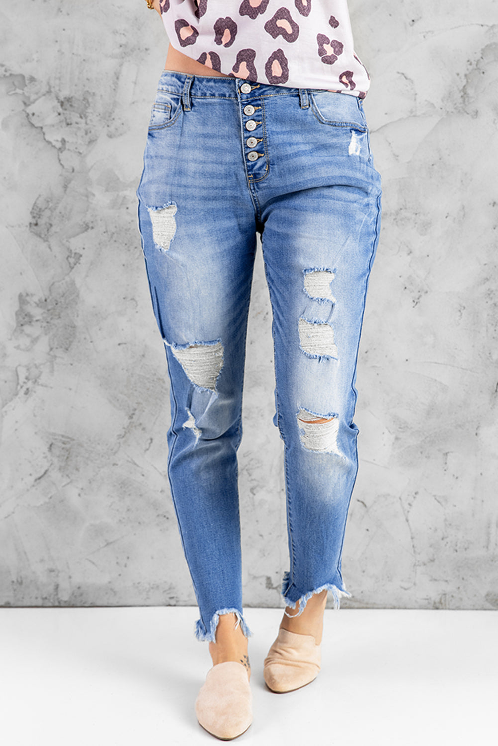 Blue high rise skinny jeans with button front and frayed ankle hem, showcasing a medium wash and distressed details.