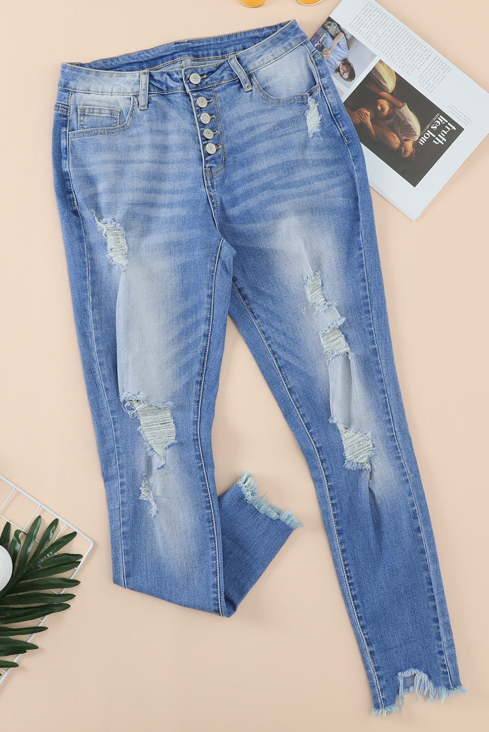 Blue high rise skinny jeans with button front and frayed ankle hem, showcasing a medium wash and distressed details.