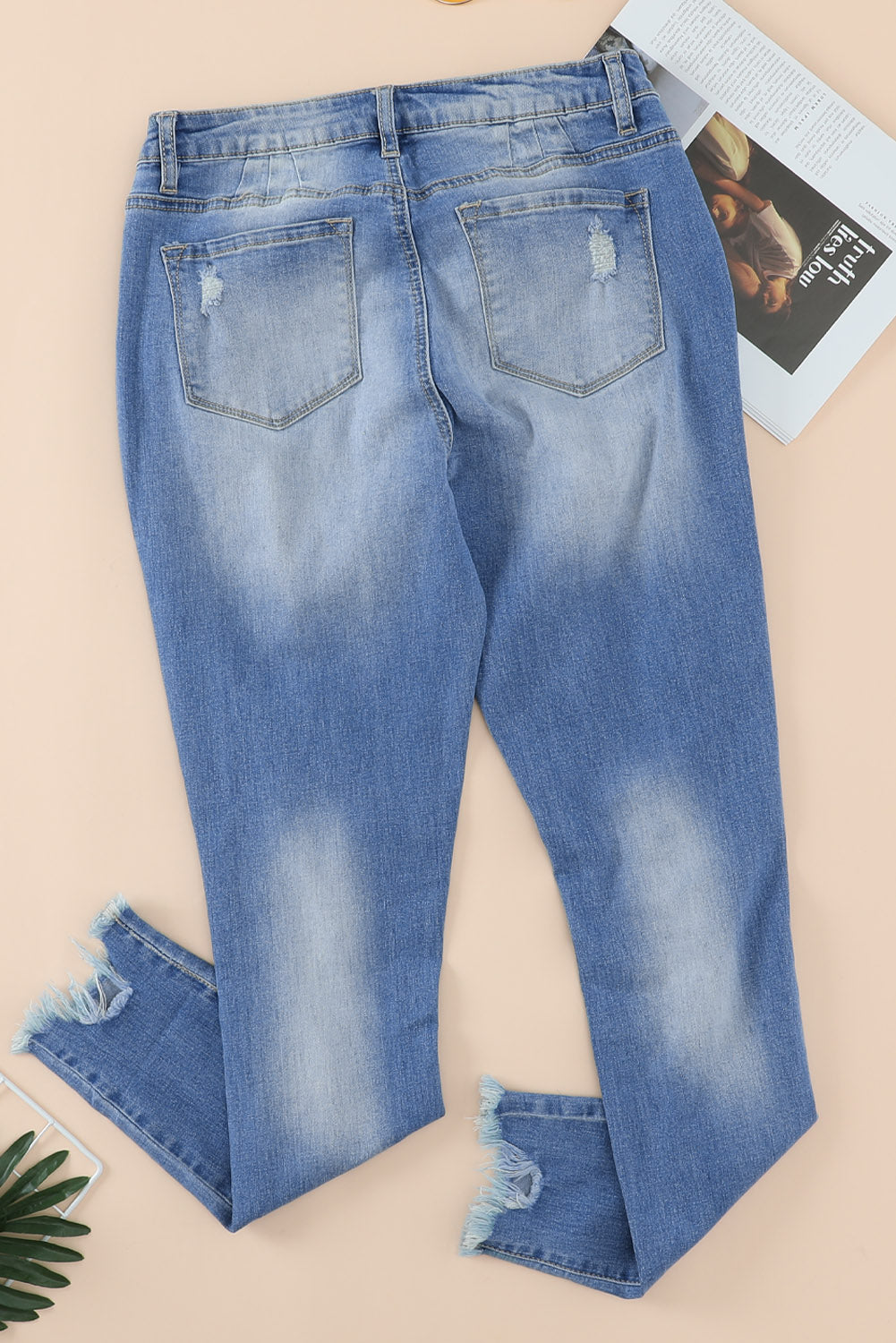 Blue high rise skinny jeans with button front and frayed ankle hem, showcasing a medium wash and distressed details.