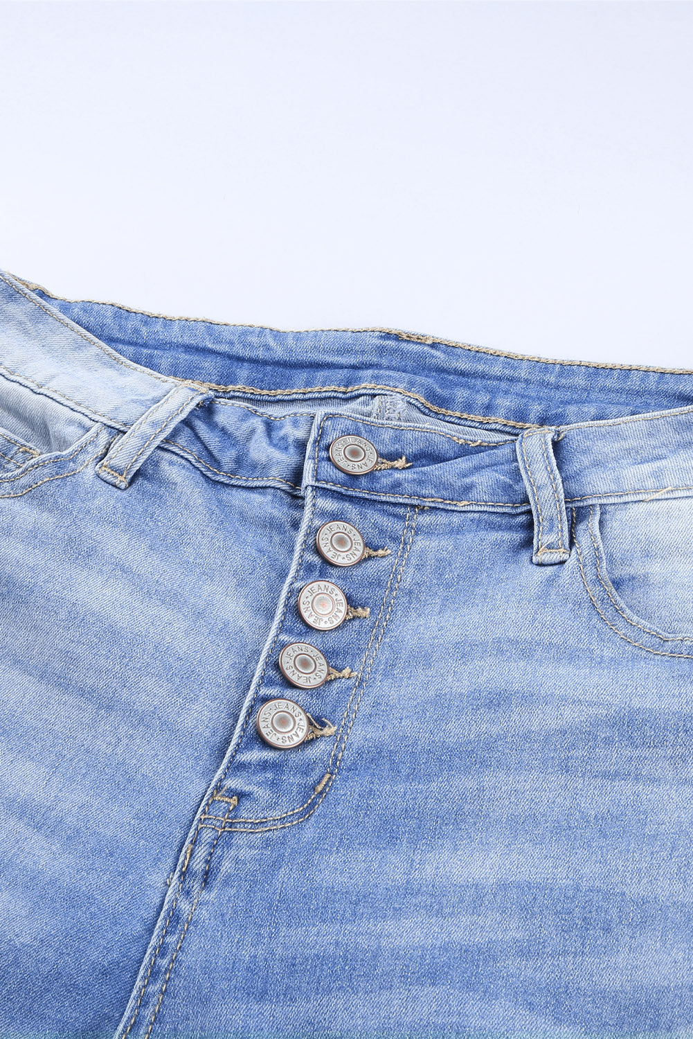 Blue high rise skinny jeans with button front and frayed ankle hem, showcasing a medium wash and distressed details.