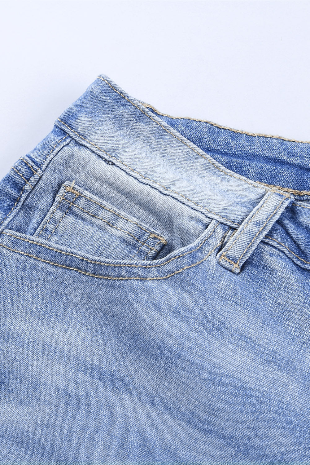 Blue high rise skinny jeans with button front and frayed ankle hem, showcasing a medium wash and distressed details.