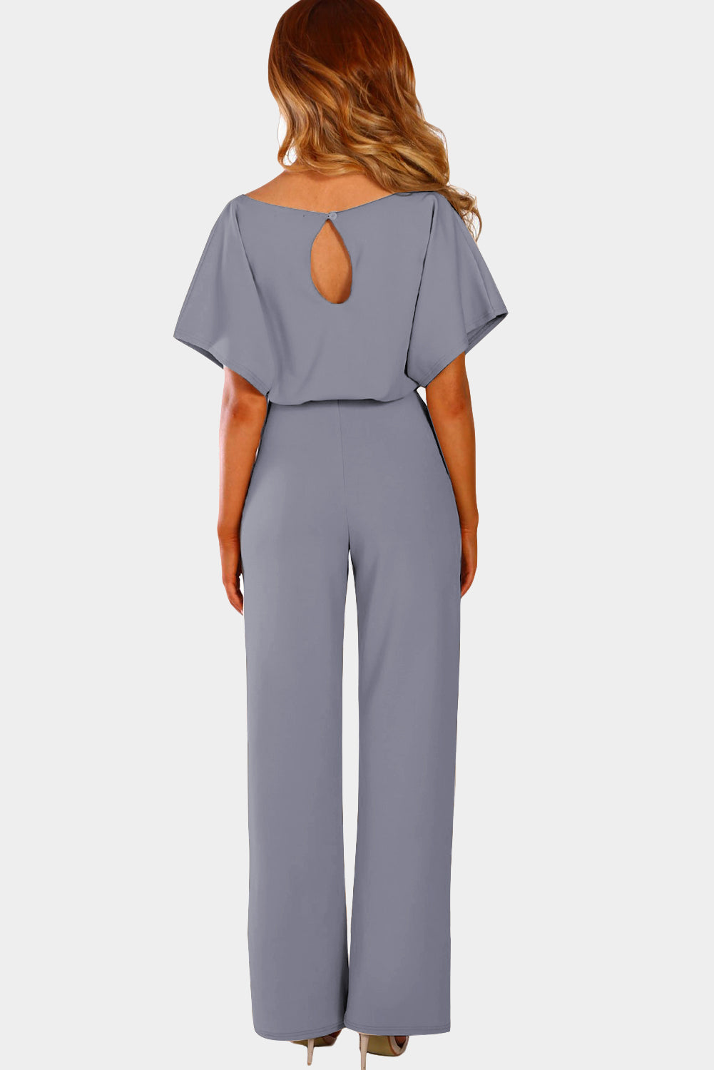 A stylish woman wearing a blue belted wide leg jumpsuit with batwing sleeves, showcasing a chic and glamorous look.