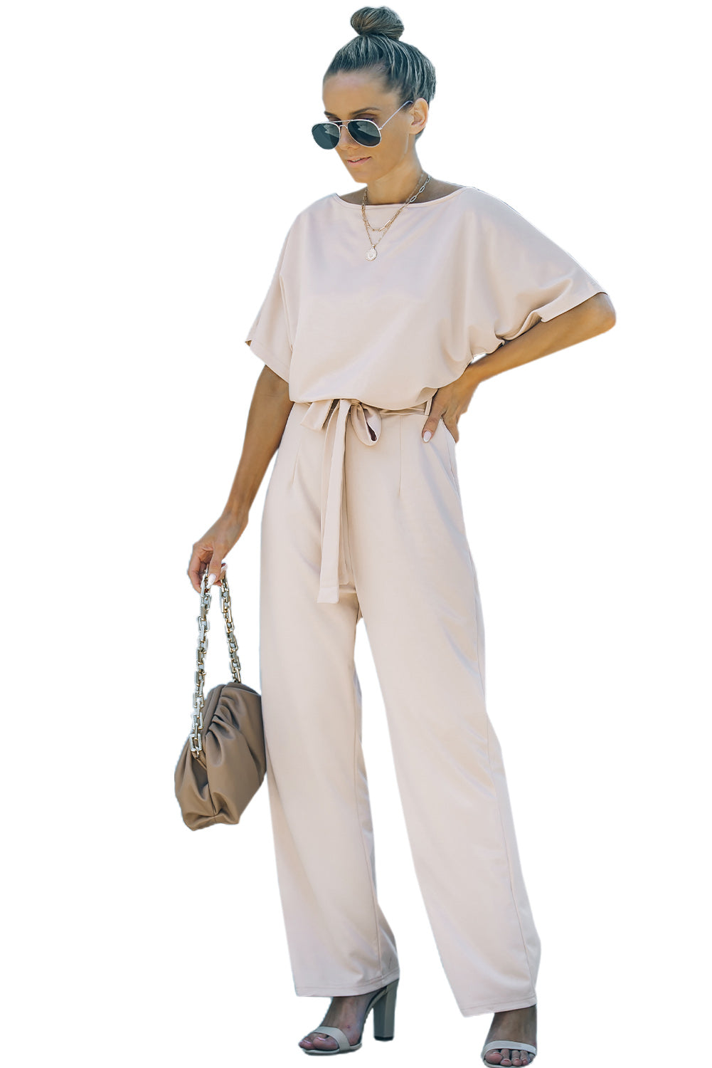 A stylish woman wearing a blue belted wide leg jumpsuit with batwing sleeves, showcasing a chic and glamorous look.