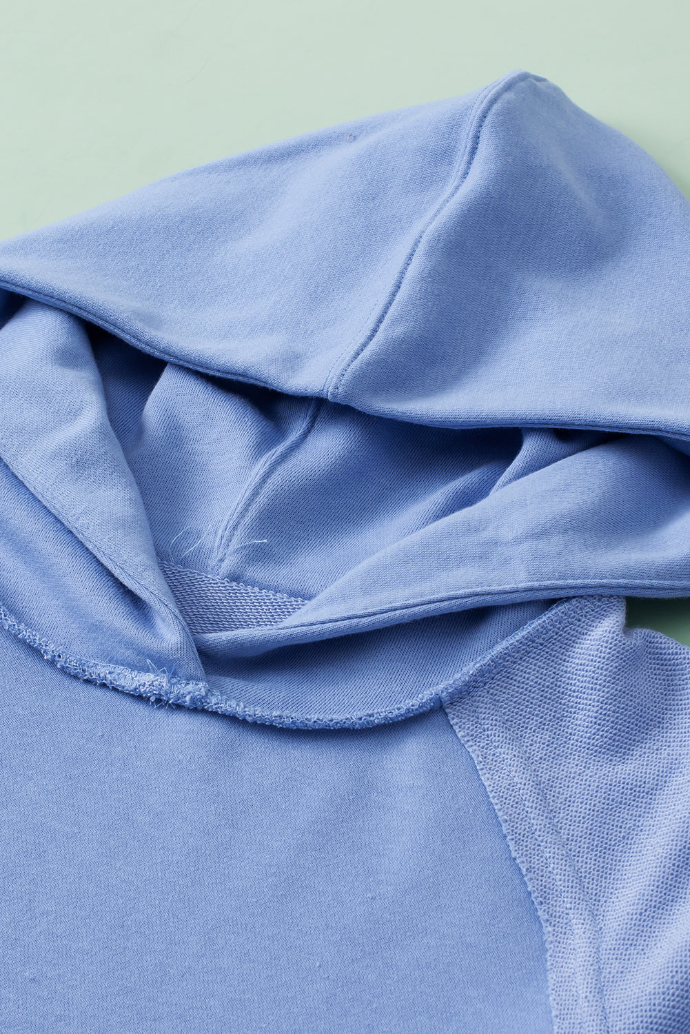 A stylish blue tunic hoodie featuring raw seams, patchwork design, and a kangaroo pocket, perfect for casual wear.