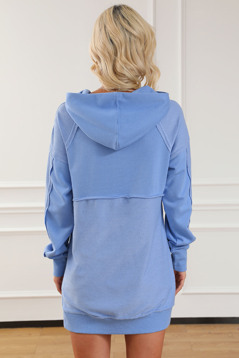 A stylish blue tunic hoodie featuring raw seams, patchwork design, and a kangaroo pocket, perfect for casual wear.