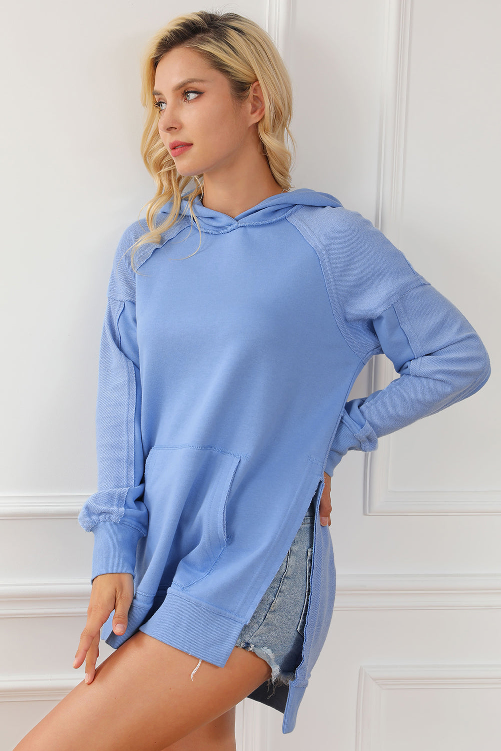 A stylish blue tunic hoodie featuring raw seams, patchwork design, and a kangaroo pocket, perfect for casual wear.