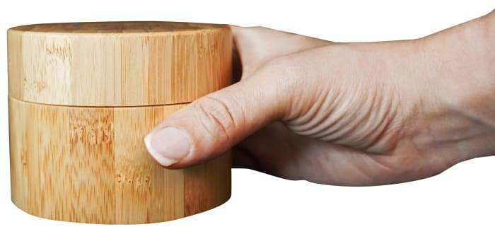 A jar of Joy Body Butter in a beautifully engraved bamboo container, showcasing its light and fluffy texture.