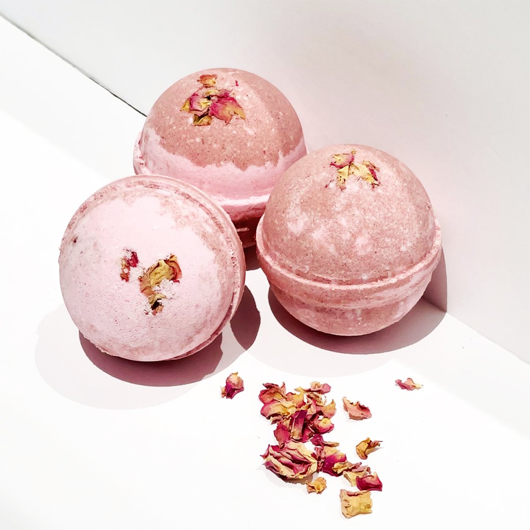 Botanic Garden Wild Rose Bath Bomb in pink water, showcasing its vibrant color and floral design.