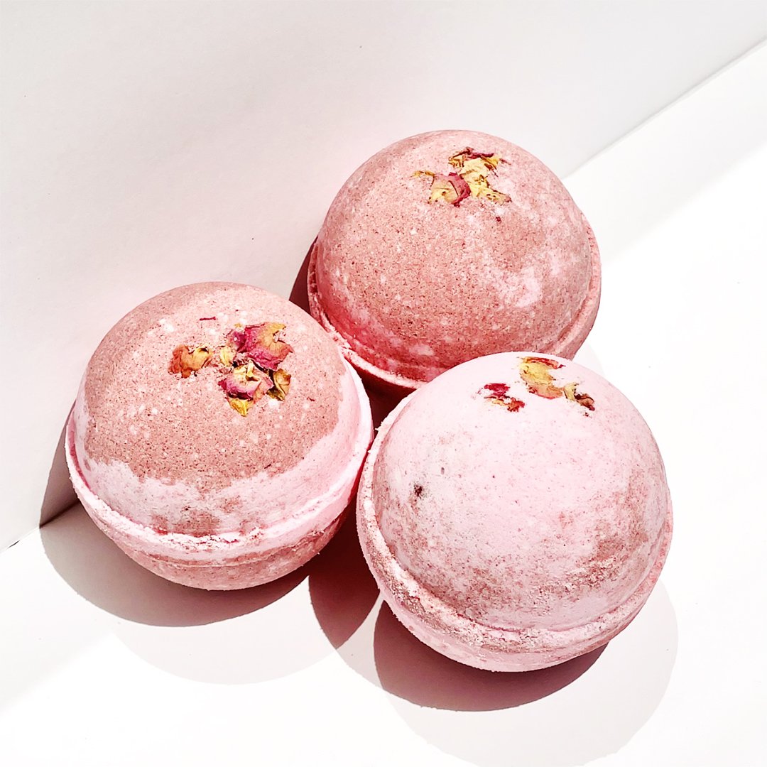 Botanic Garden Wild Rose Bath Bomb in pink water, showcasing its vibrant color and floral design.