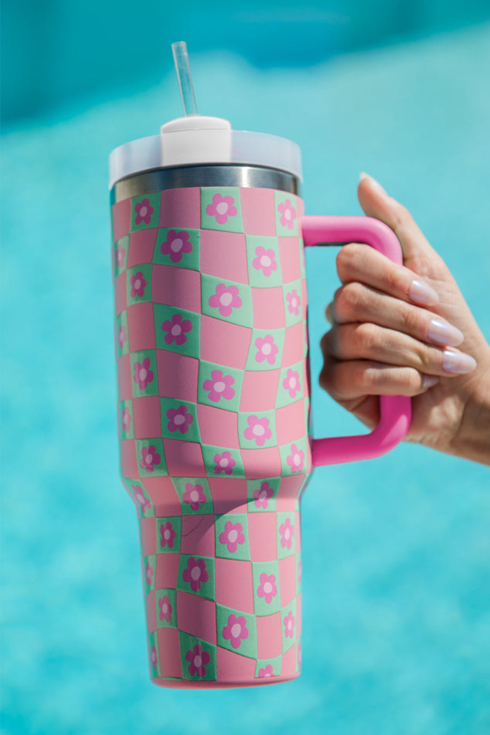 Bright pink cup with a checkered pattern and floral design, featuring a reusable straw, perfect for drinks.