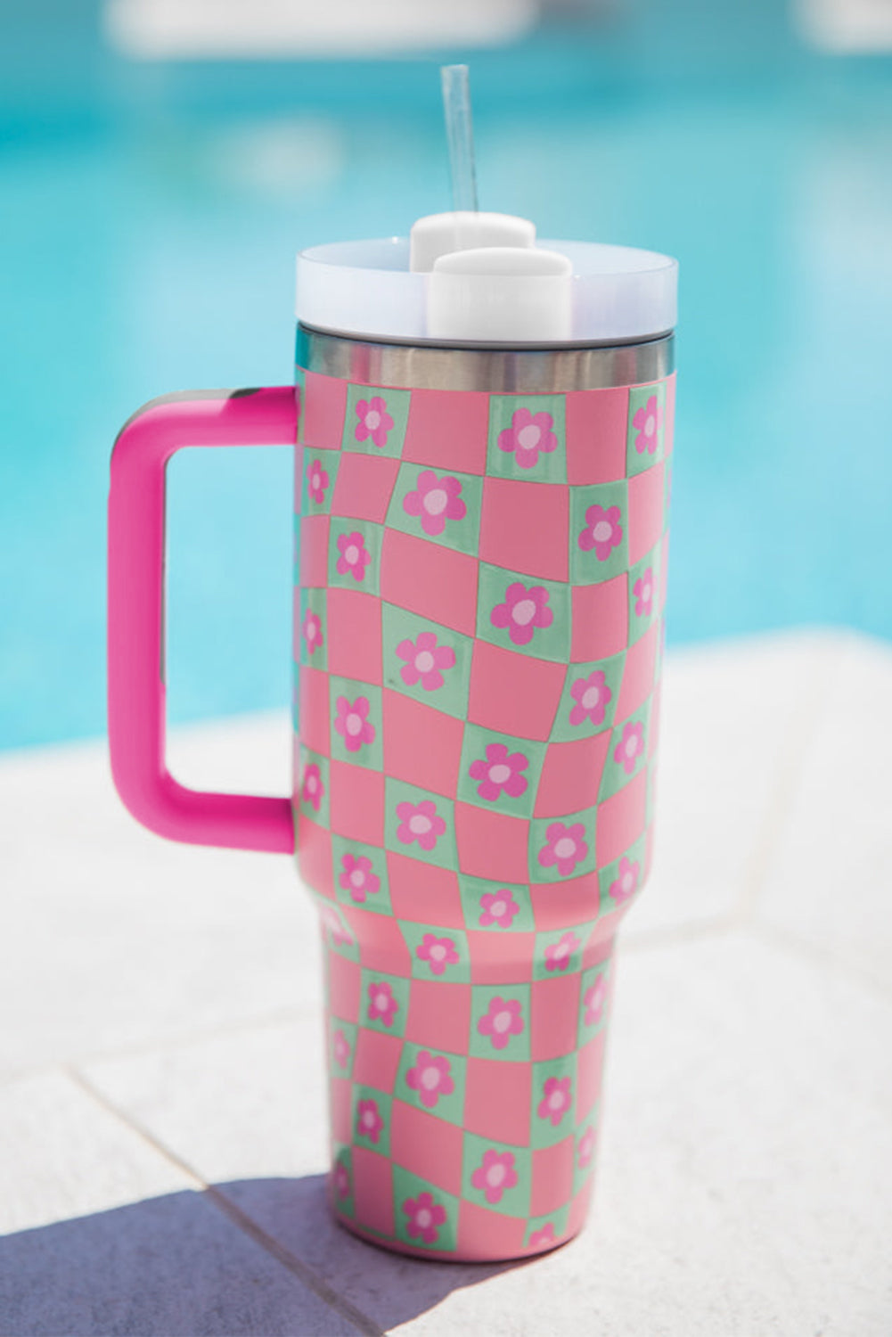 Bright pink cup with a checkered pattern and floral design, featuring a reusable straw, perfect for drinks.