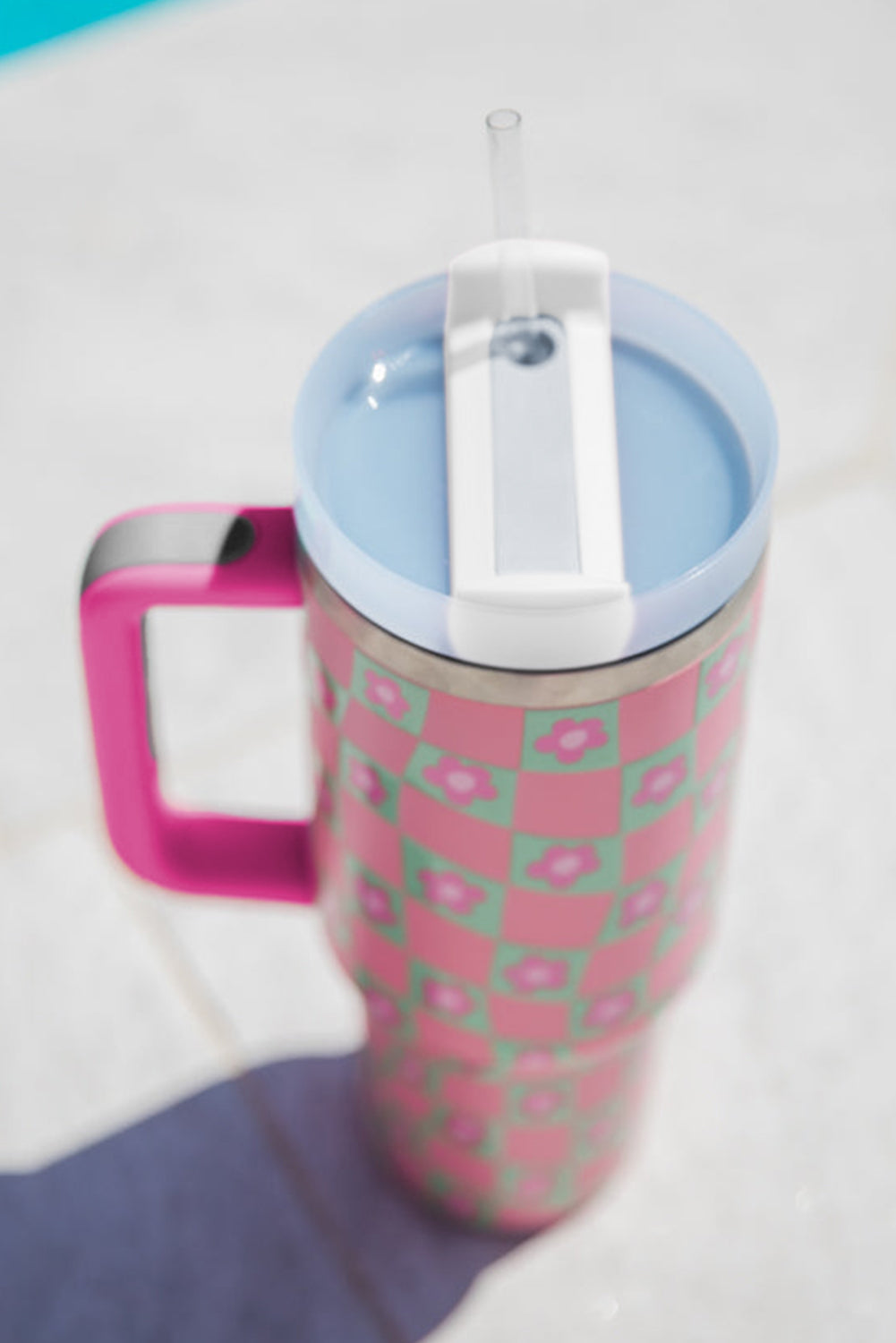 Bright pink cup with a checkered pattern and floral design, featuring a reusable straw, perfect for drinks.