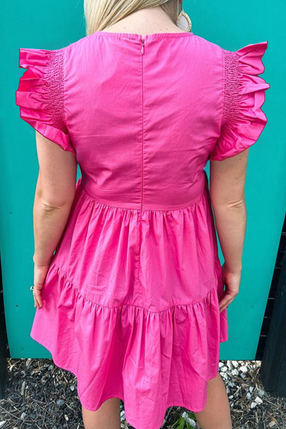 Bright pink ruffled babydoll mini dress displayed on a mannequin, showcasing its playful design and vibrant color.