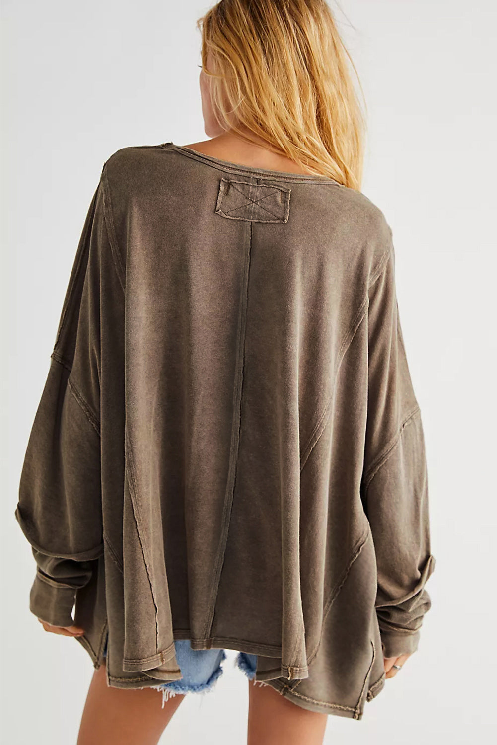 Brown sweatshirt with exposed seams and thumbholes, featuring a drop shoulder design for a relaxed fit.