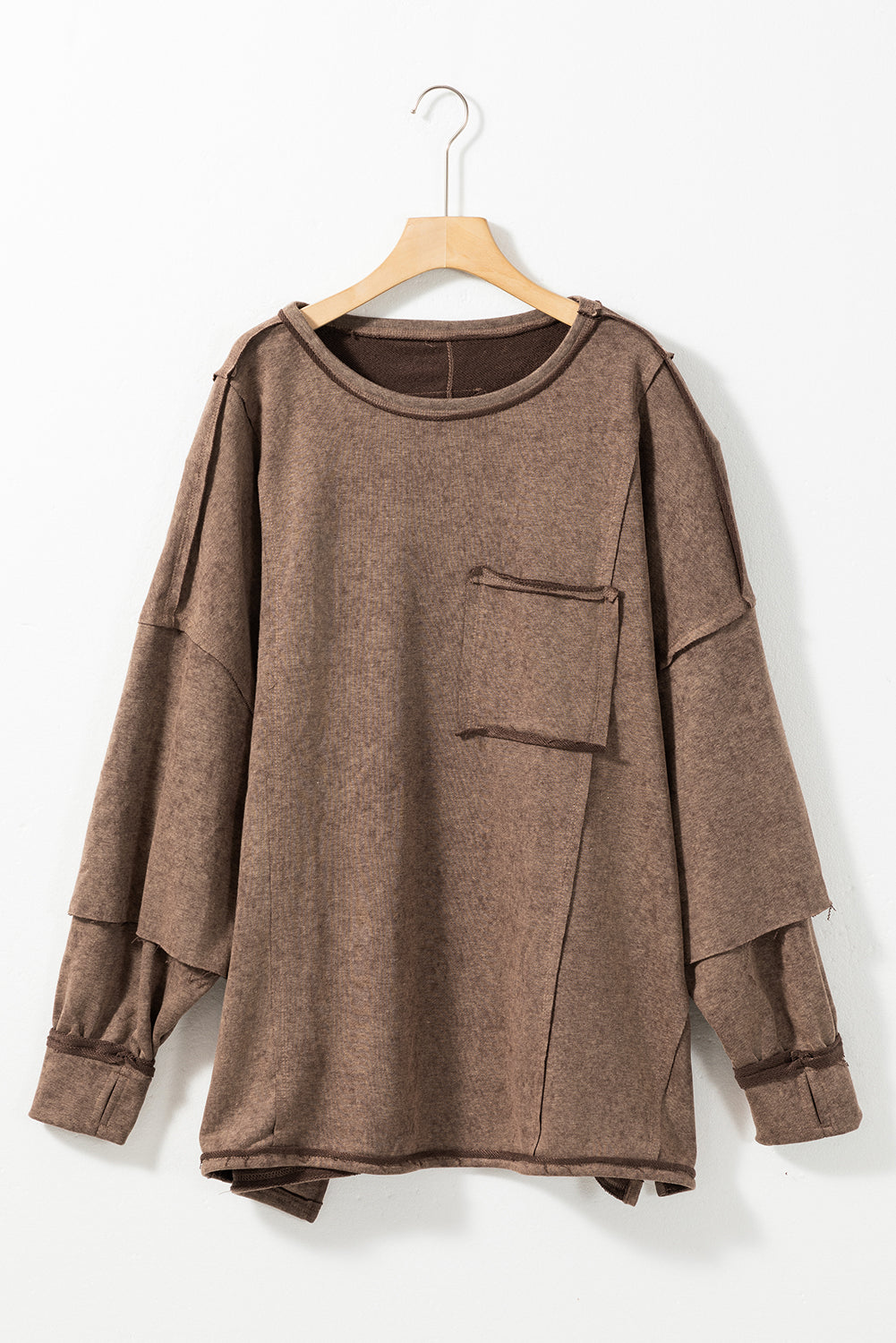 Brown sweatshirt with exposed seams and thumbholes, featuring a drop shoulder design for a relaxed fit.