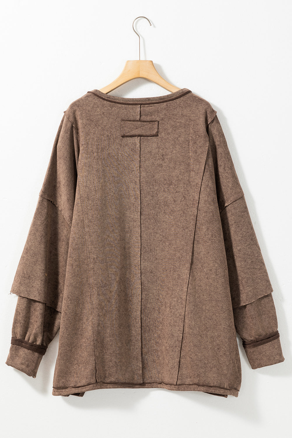 Brown sweatshirt with exposed seams and thumbholes, featuring a drop shoulder design for a relaxed fit.