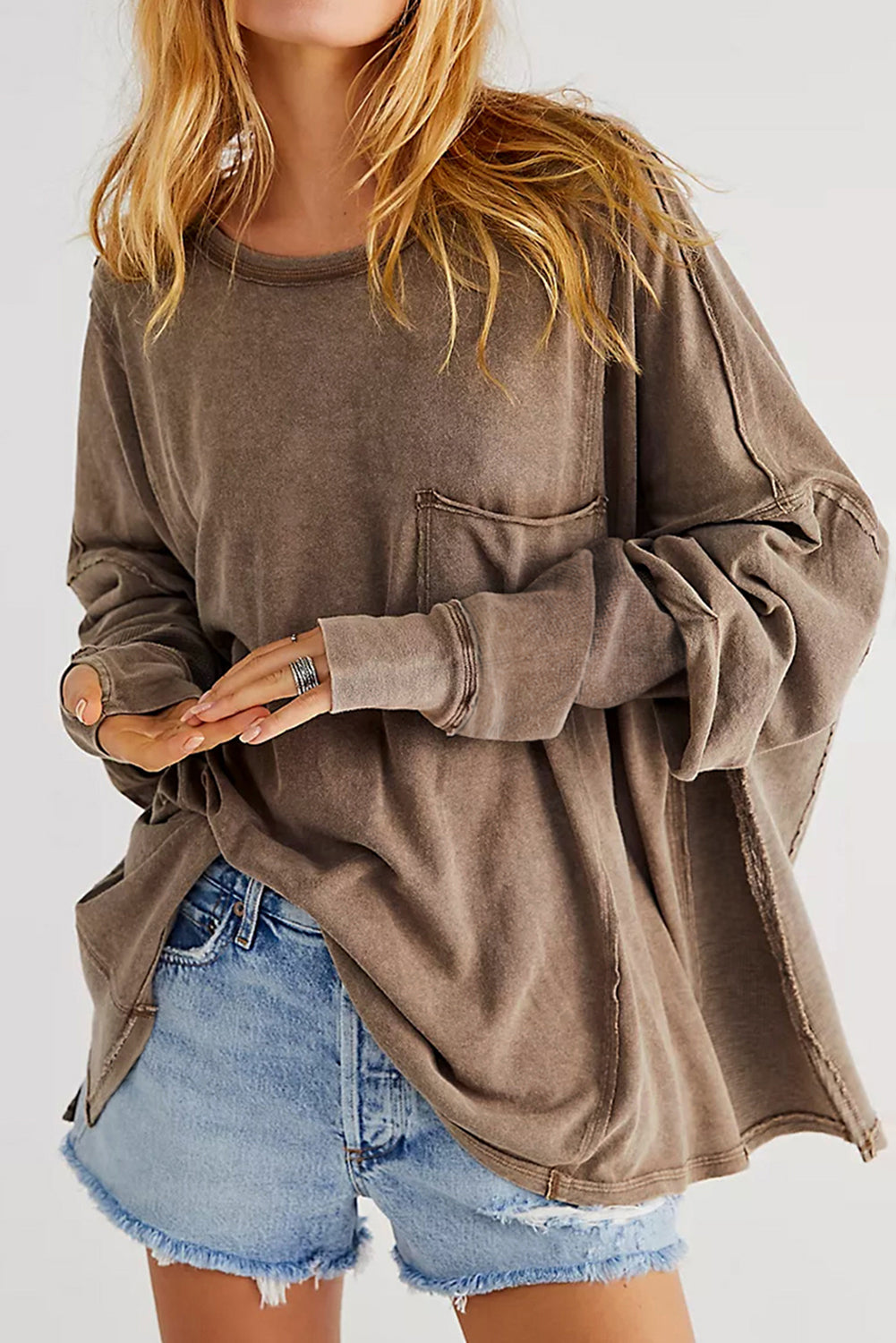 Brown sweatshirt featuring exposed seams, thumbholes, and drop shoulder design, perfect for a relaxed and stylish look.