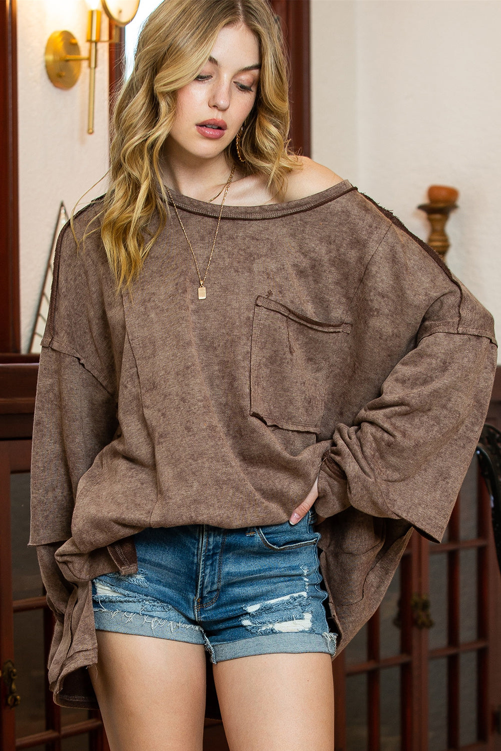 Brown sweatshirt featuring exposed seams, thumbholes, and drop shoulder design, perfect for a relaxed and stylish look.